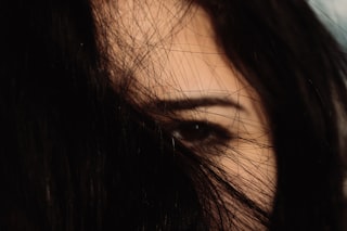 Close-up of a woman's eye peeking through dark hair